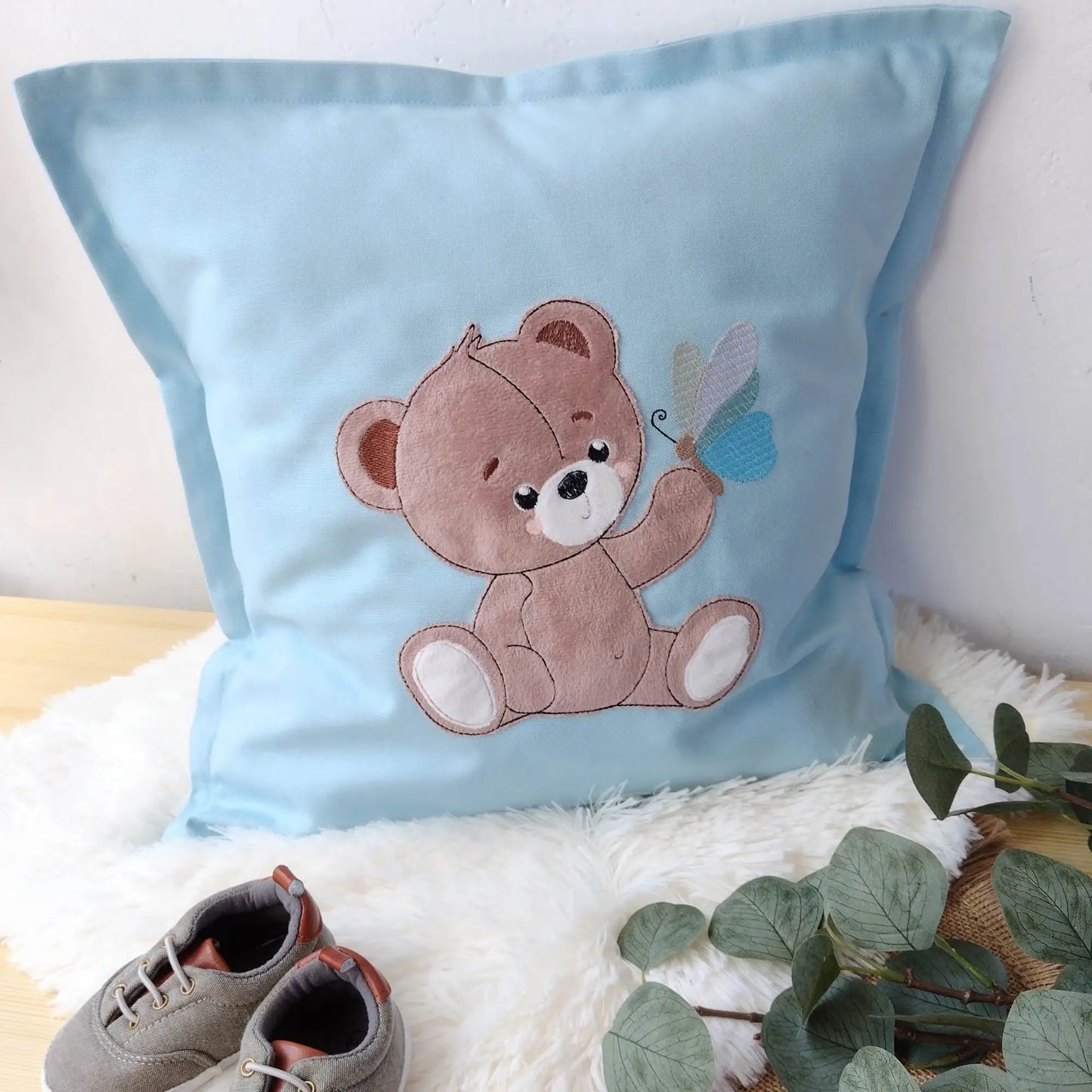 Medvedik s motýľom na modrom vankúši